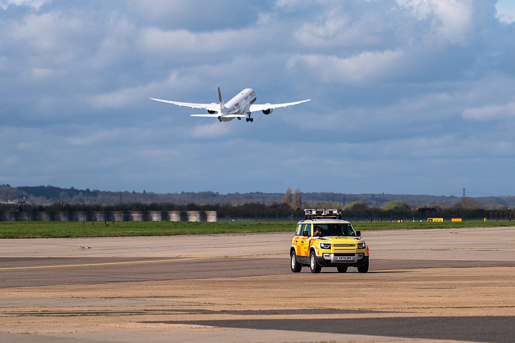Gulf Air departing 27L with an airfield operations car driving. Gulf Air departing 27L with an airfield operations car driving